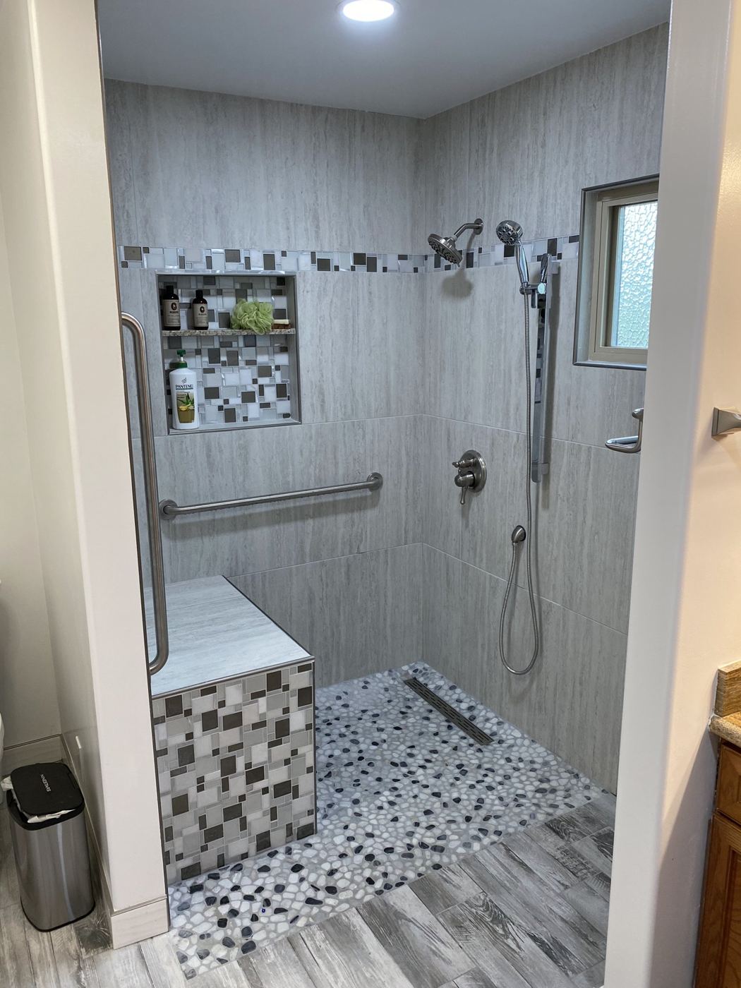 Curbless walk-in shower with bench, grab bars and pebble floor